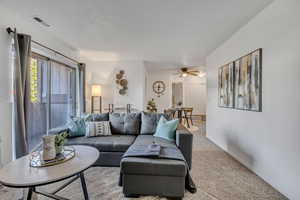 Carpeted living room with ceiling fan and baseboards