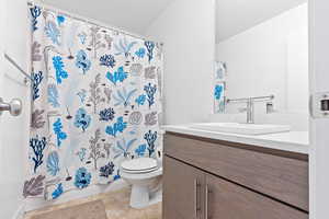 Bathroom featuring tile patterned floors, shower / bathtub combination with curtain, vanity, and toilet