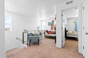 Corridor with visible vents, an upstairs landing, carpet, and a healthy amount of sunlight
