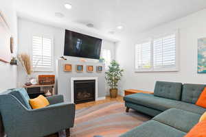 Living area featuring recessed lighting, baseboards, wood finished floors, and a glass covered fireplace