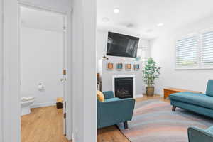 Living room featuring a glass covered fireplace, light wood-style floors, and baseboards