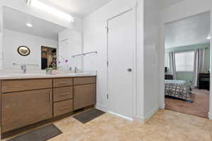 Full bath featuring double vanity, ensuite bathroom, a sink, and baseboards