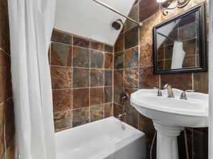 Bathroom featuring tile walls and shower / tub combo