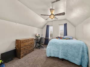 Bedroom featuring a textured ceiling, vaulted ceiling, visible vents, ceiling fan, and carpet floors