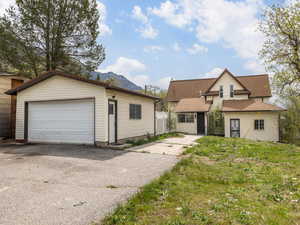 View of front facade featuring a mountain view, an outbuilding, and a garage