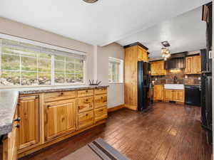 Kitchen with baseboards, a sink, black appliances, and dark wood-style flooring