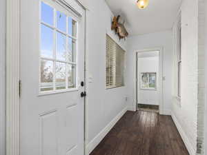 Doorway with dark wood finished floors and baseboards