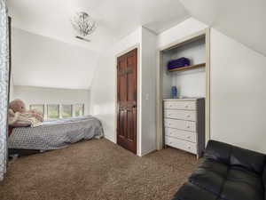 Bedroom featuring lofted ceiling, visible vents, and carpet flooring