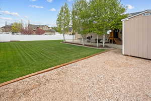 View of yard with fence, a shed, and a patio