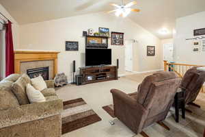 Great room with vaulted ceiling, ceiling fan, arched walkways, and a tiled fireplace