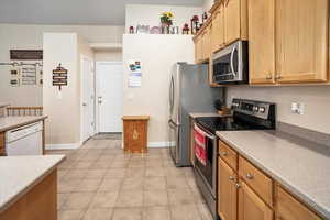 Kitchen with light tile patterned floors, baseboards, stainless steel appliances, and light countertops