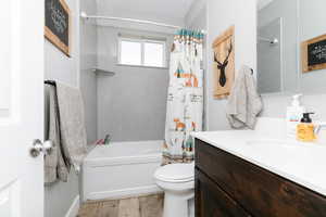Full bath featuring vanity, shower / bath combo, and wood finished floors