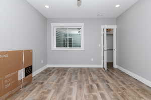 Unfurnished bedroom featuring wood finished floors, recessed lighting, and a walk in closet
