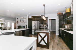 Kitchen featuring appliances with stainless steel finishes, a kitchen island with sink, recessed lighting, tasteful backsplash, and light countertops