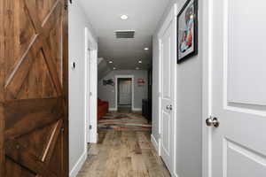 Corridor featuring light wood-style flooring, recessed lighting, and a textured ceiling