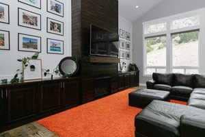 Living room featuring lofted ceiling, healthy amount of natural light, a large fireplace, recessed lighting, and wood finished floors