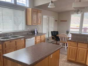 Kitchen with dark countertops, a healthy amount of sunlight, dishwasher, and a sink