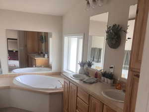 Bathroom featuring double vanity, a garden tub, carpet floors, and a sink