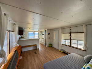 Bedroom with freestanding refrigerator, wood finished floors, and a textured ceiling