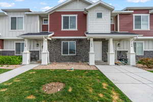 View of property with stone siding, a front lawn, and board and batten siding