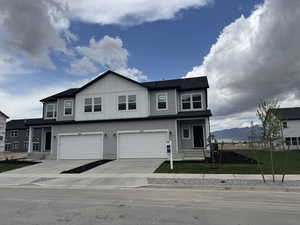 View of front facade featuring concrete driveway, board and batten siding, a mountain view, an attached garage, and a front lawn