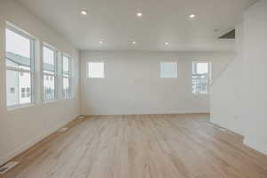 Empty room featuring baseboards, light wood-style flooring, visible vents, and a wealth of natural light