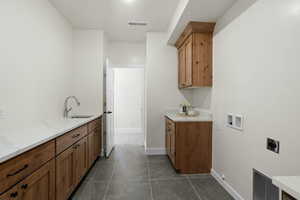 Clothes washing area featuring a sink, dark tile patterned flooring, hookup for an electric dryer, visible vents, and washer hookup