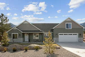 Craftsman-style house with board and batten siding, a porch, stone siding, and concrete driveway