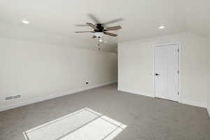 Bonus room featuring lofted ceiling, visible vents, carpet flooring, and ceiling fan
