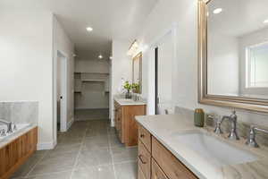 Full bath with recessed lighting, two vanities, a garden tub, and a sink