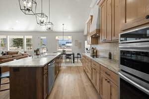 Kitchen with a center island with sink, a notable chandelier, decorative backsplash, appliances with stainless steel finishes, and a breakfast bar area