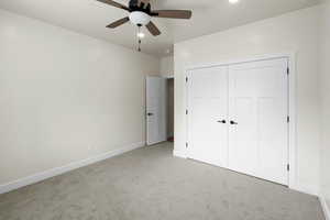 Unfurnished bedroom featuring a ceiling fan, light carpet, a closet, and baseboards