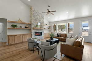 Living room with high vaulted ceiling, a ceiling fan, light wood-style flooring, a fireplace, and recessed lighting