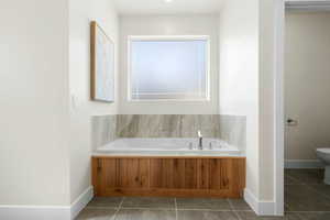 Full bathroom featuring tile patterned floors, a garden tub, baseboards, and toilet