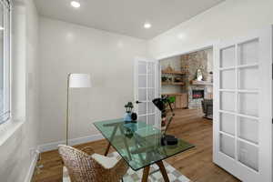 Home office featuring french doors, baseboards, recessed lighting, wood finished floors, and a stone fireplace
