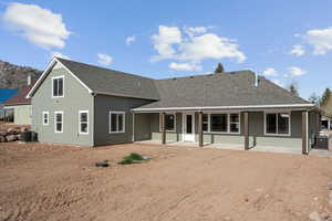 Rear view of property featuring a patio area, roof with shingles, central AC, and driveway
