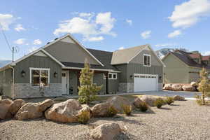 Craftsman house with concrete driveway, an attached garage, board and batten siding, stone siding, and roof with shingles