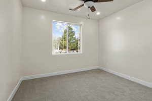Empty room featuring carpet floors, visible vents, a ceiling fan, and baseboards