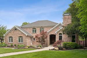 View of front facade featuring brick siding, a shingled roof, and a chimney