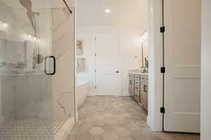 Bathroom with a freestanding tub, a marble finish shower, recessed lighting, and vanity