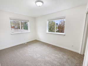 Spare room with a textured ceiling, carpet, visible vents, and baseboards