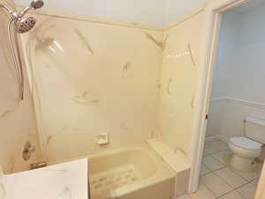 Bathroom with toilet, tile patterned floors, and  shower combination