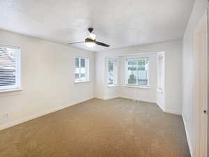 Unfurnished room with light carpet, a textured ceiling, visible vents, baseboards, and ceiling fan