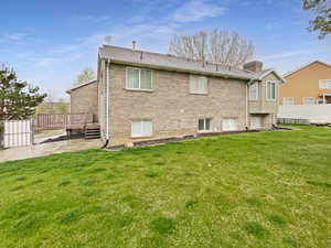Back of house with a chimney, a wooden deck, a patio area, and a yard