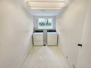 Laundry room with light floors, laundry area, visible vents, independent washer and dryer, and baseboards