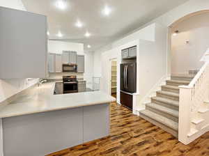 Kitchen featuring visible vents, gray cabinetry, arched walkways, and appliances with stainless steel finishes