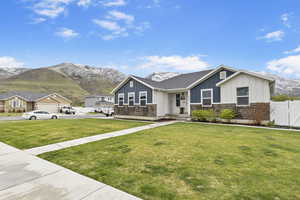 View of front of home featuring a mountain view, fence, board and batten siding, and a front yard