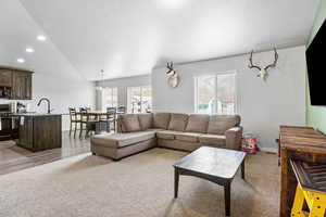 Living area with recessed lighting, lofted ceiling, baseboards, and light carpet