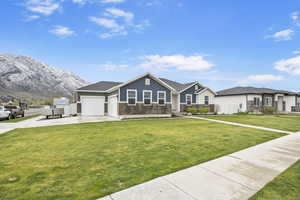 Ranch-style house with a front lawn, concrete driveway, board and batten siding, a mountain view, and a garage