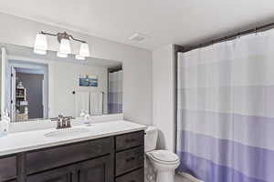 Bathroom with visible vents, toilet, vanity, and a shower with curtain